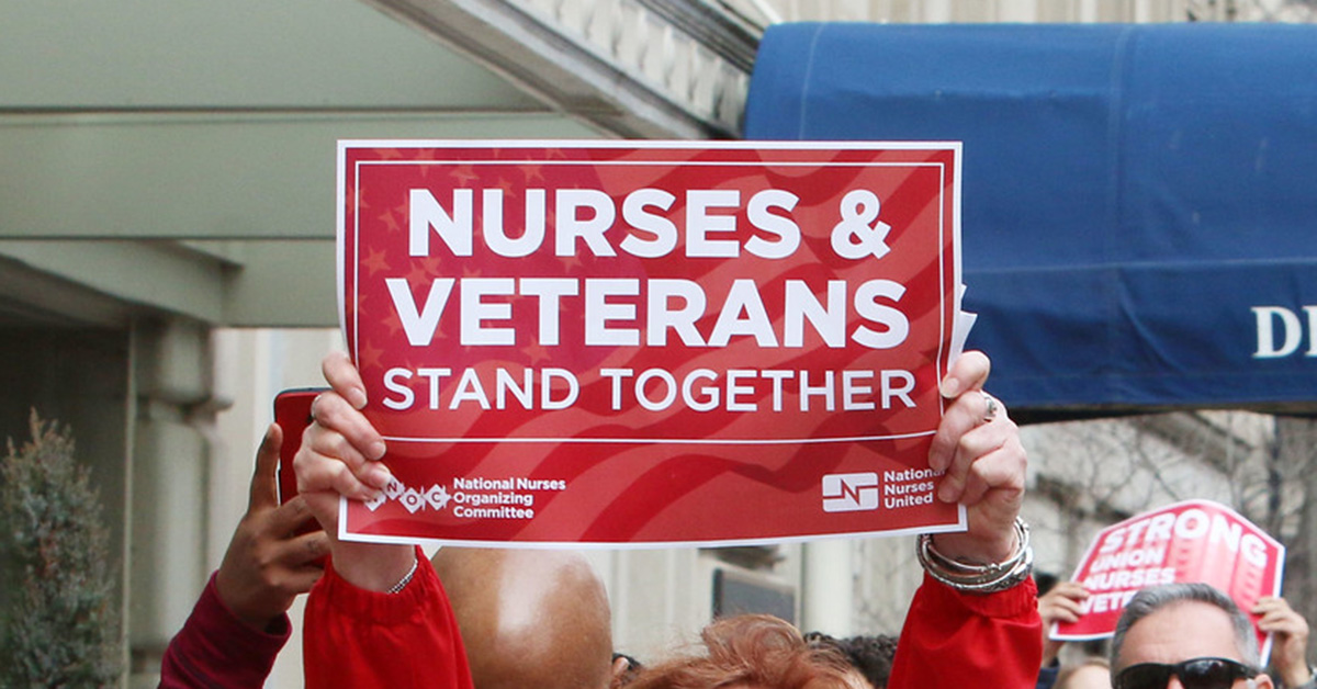 Nurse holds sign "Nurses & Veterans Stand Together"