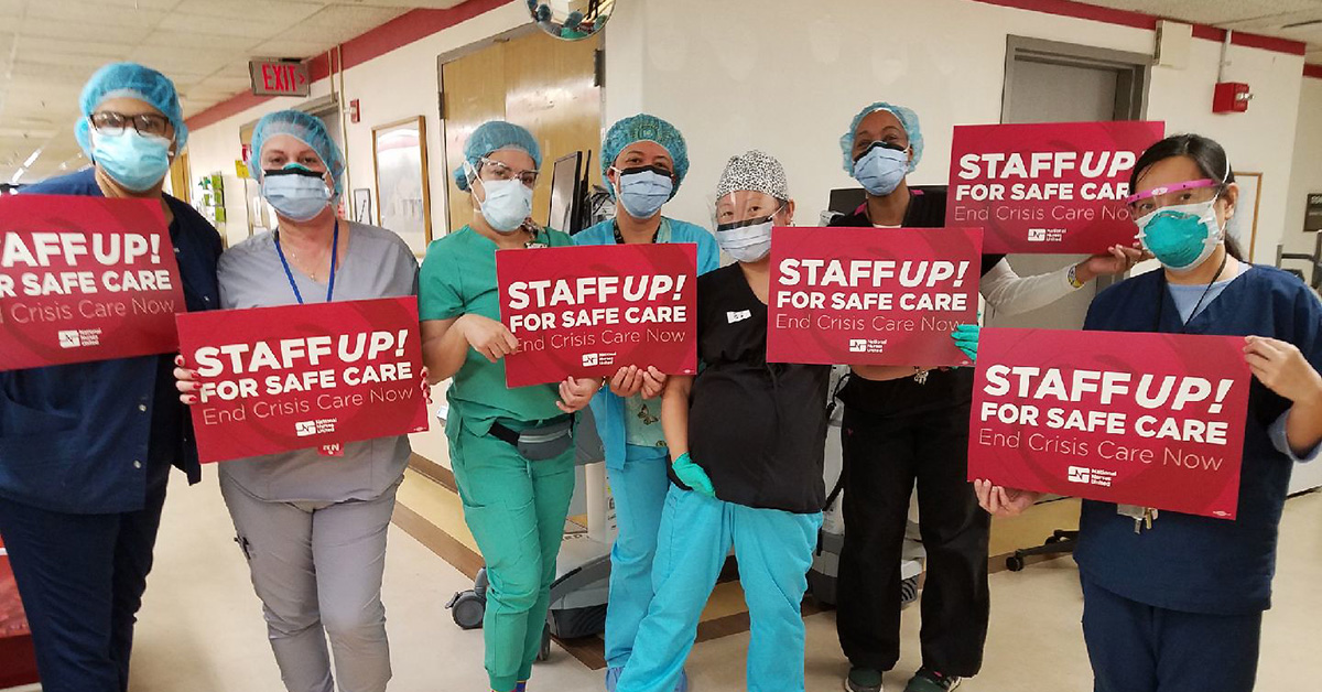 Group of nurses inside hospital hold signs "Staff up for safe patient care"