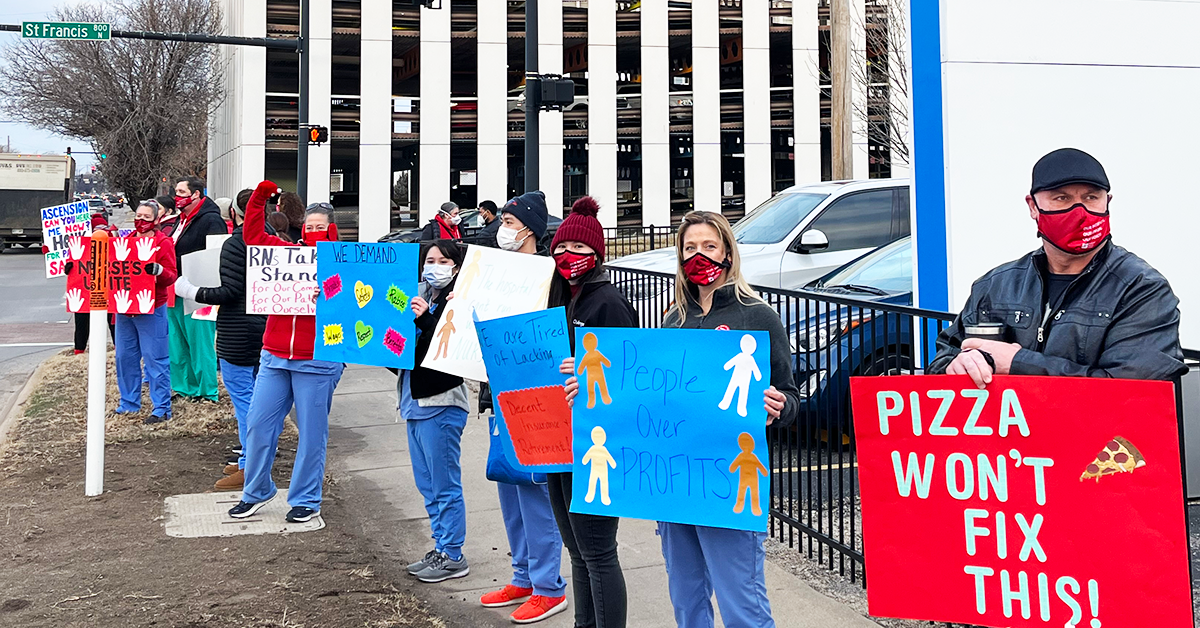 Nurses in front of St. Francis holding signs