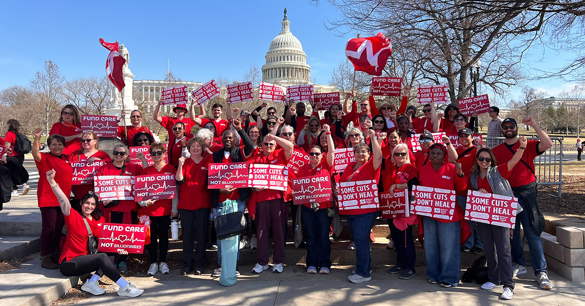 Seven nurses standing in front of U.S. capitol building, smiling, with raised fists, holding signs "Some Cuts Don't Heal"