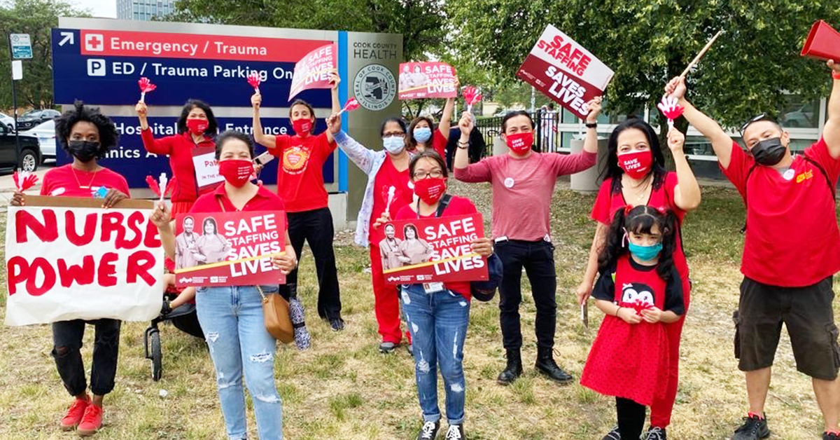 Nurses and community outside Cook County ER with signs "Safe Staffing Saves Lives" and "Nurse Power"