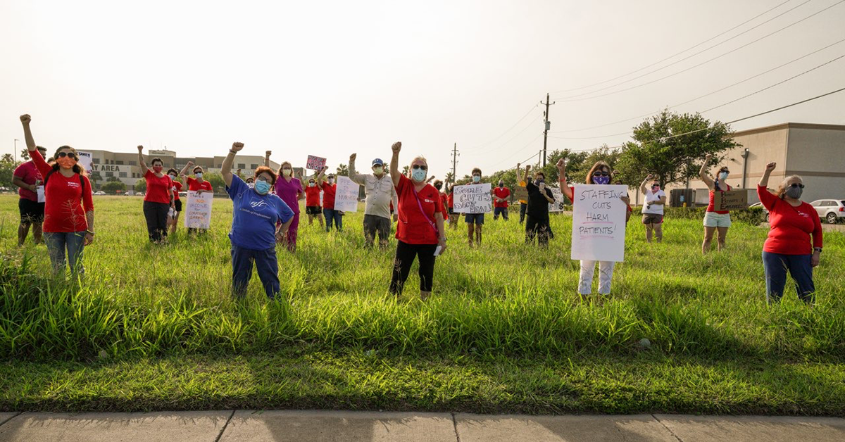 Large group of Corpus Christi nurses hold raised fists in field