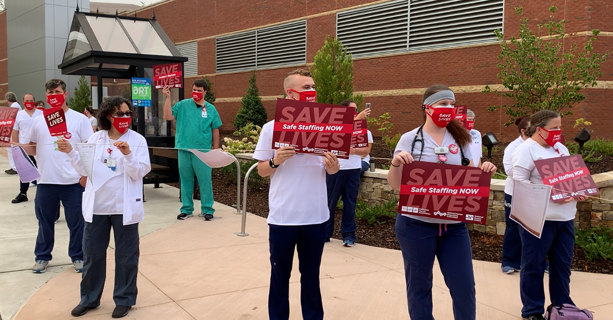 Nurses outside mission hospital hold signs calling for safe staffing