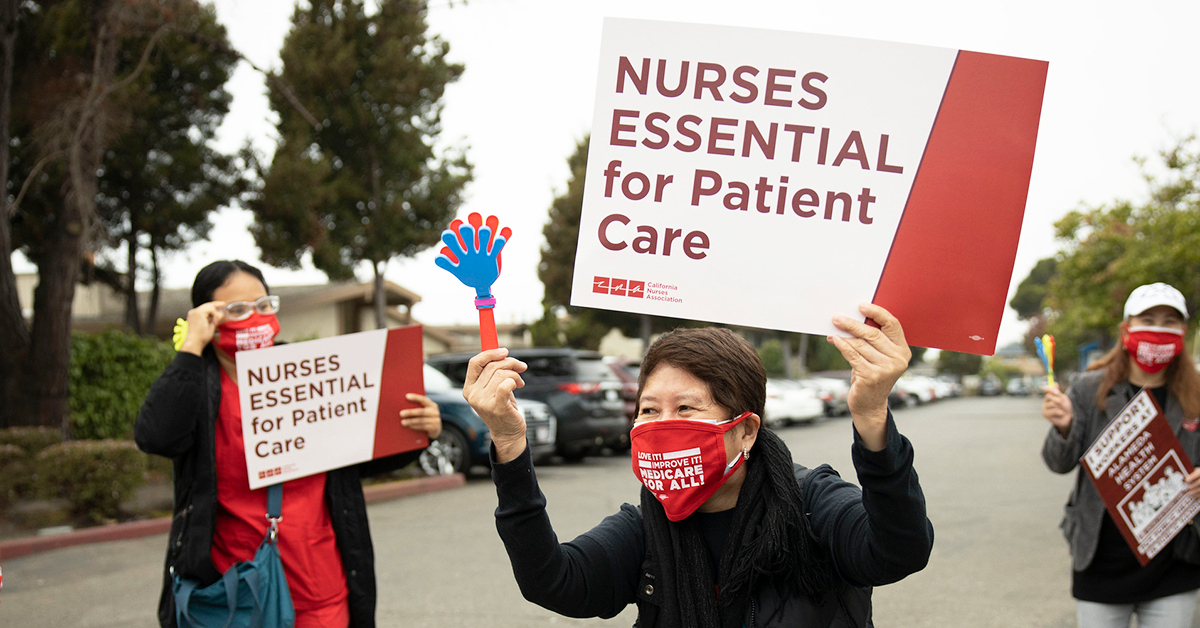 Nurses hold signs "Nurses essential for patient care"
