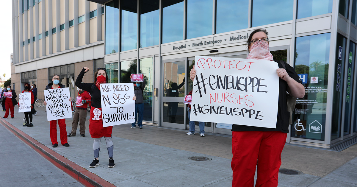 Nurses hold signs calling for PPE