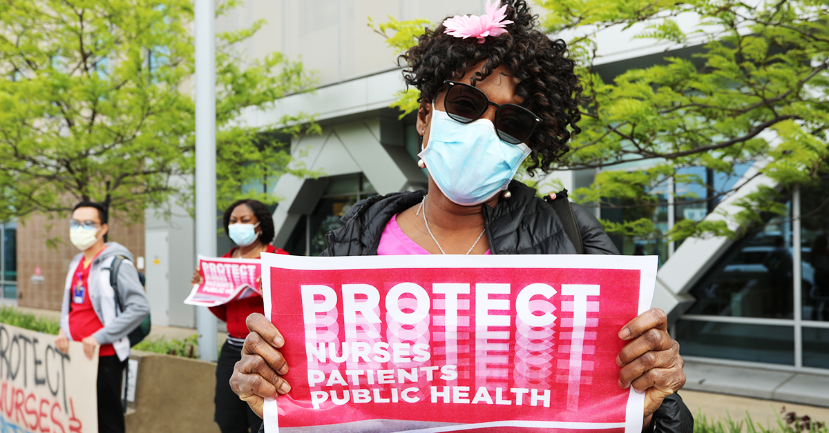 Nurse holding sign with "Protect Nurses/Patients/Publich Health"