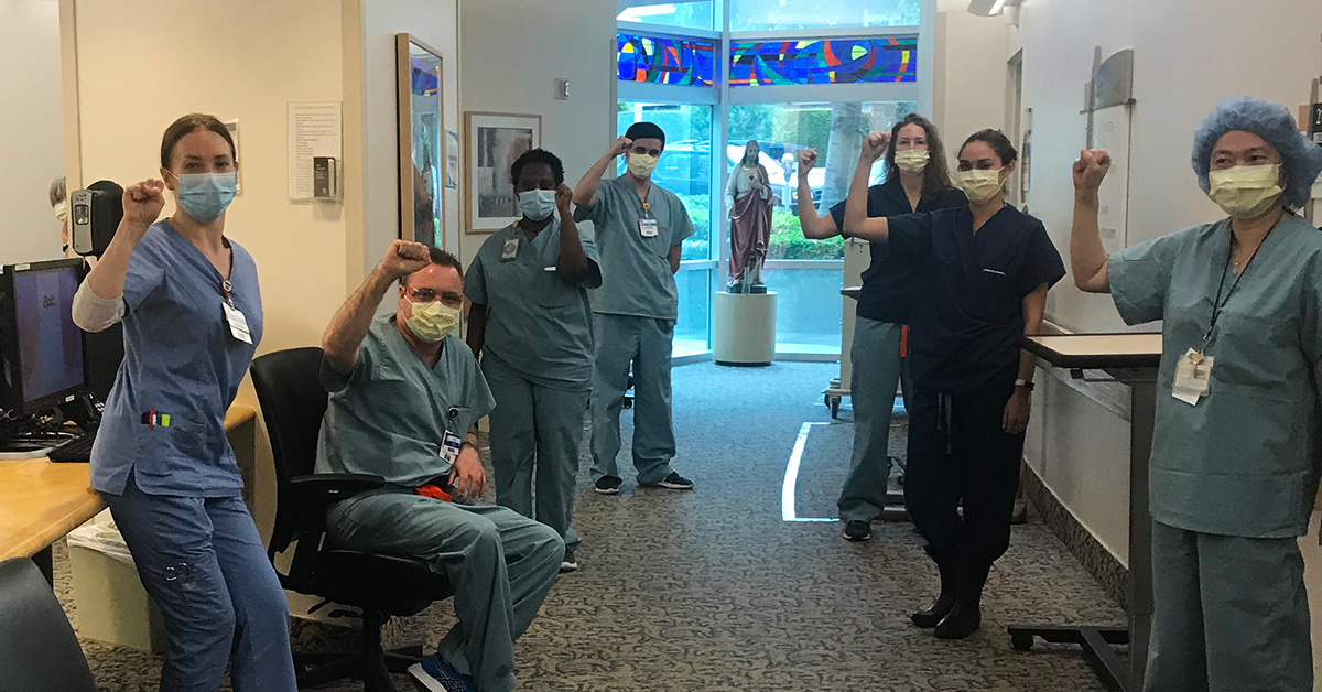 Group on nurses inside hospital hold raised fists