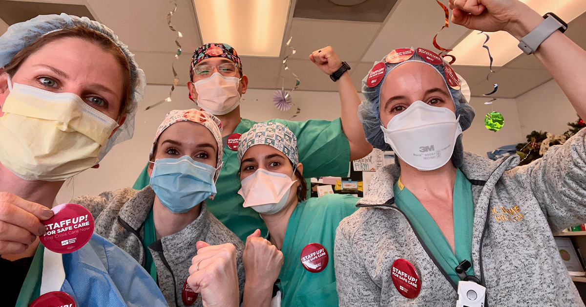 Group of nurses inside hospital hold raised fists