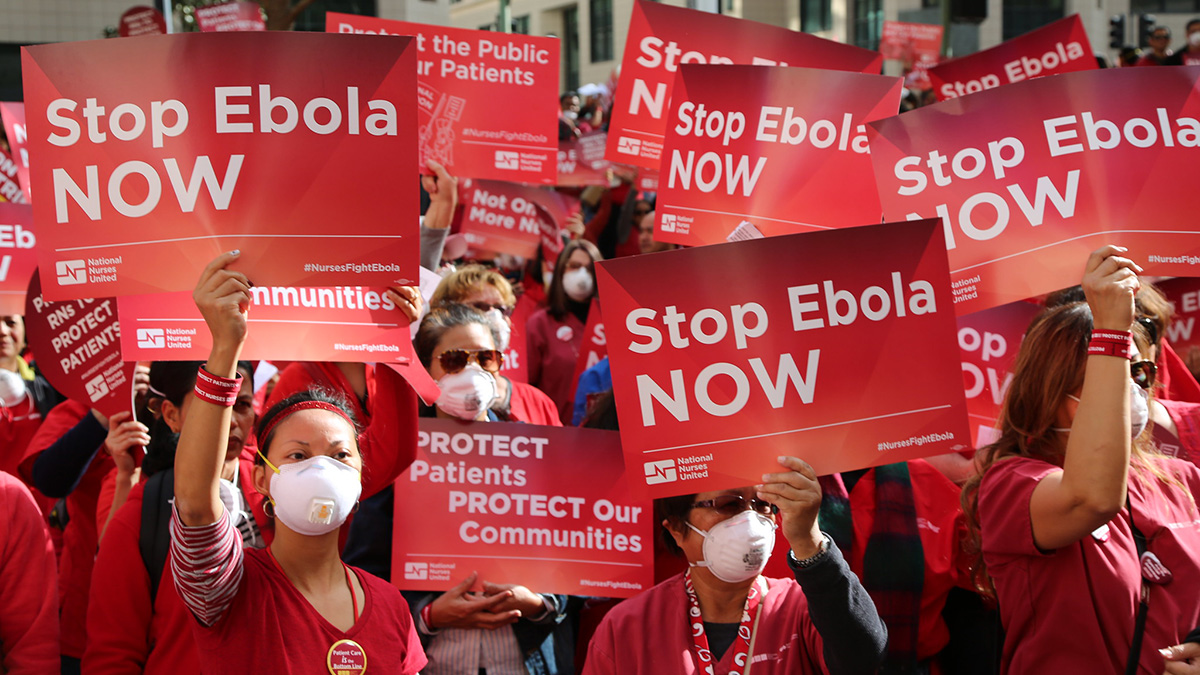Nurses hold signs "Stop Ebola Now"