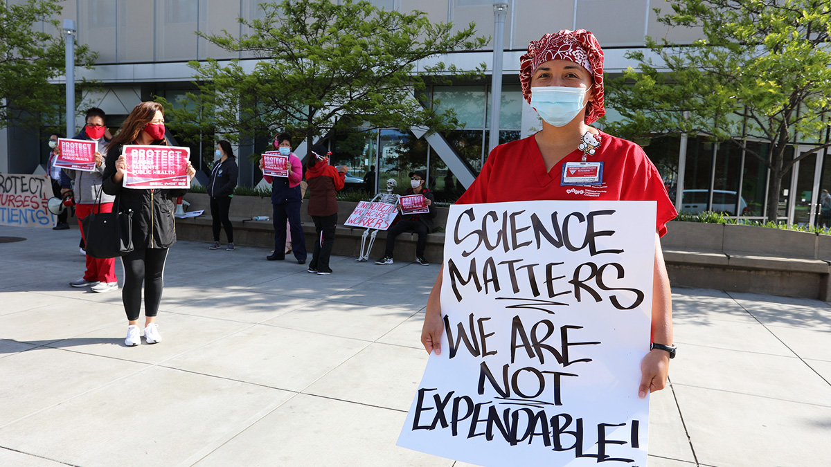 Nurse holds sign "Science Matters, We Are Not Expendable"