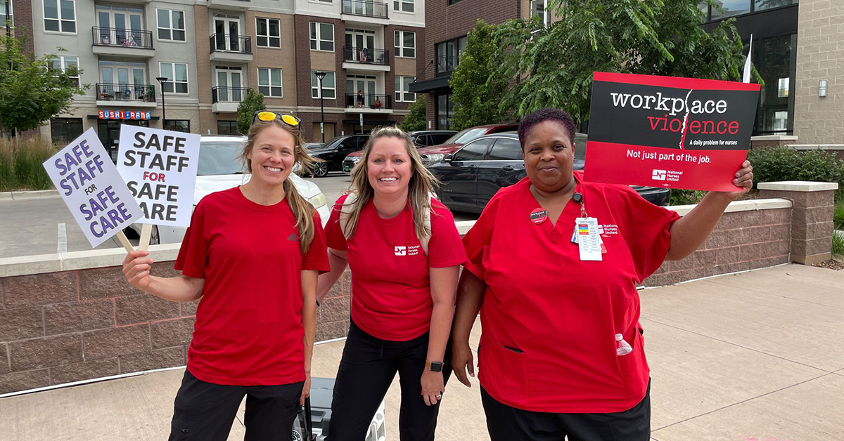 Three nurses holding signs calling for safety from workplace violence