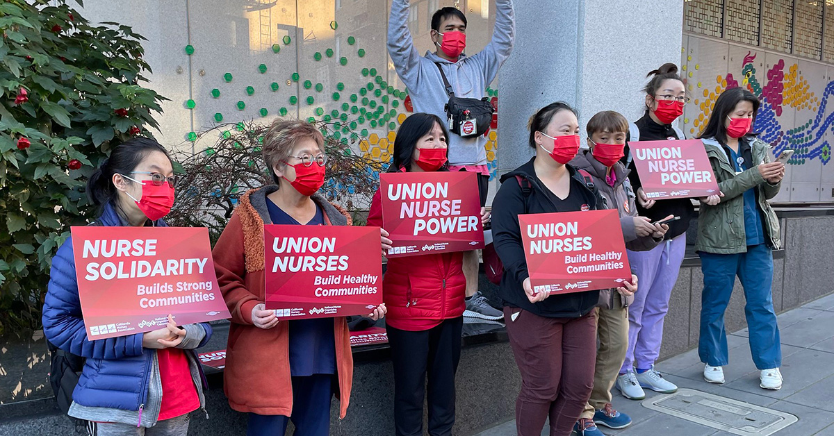Group of nurses outside Chinese Hospital holding signs "Union Nurses Build Healthy Communities"