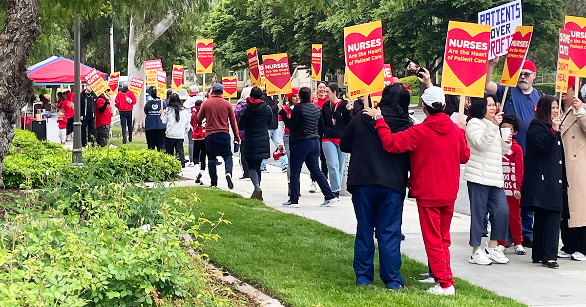 Nurses holding signs on a grassy knoll and sidewalk: "Nurses are the heart of patient care"