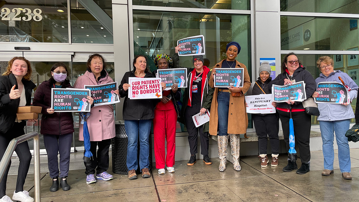 Group of nurses outside hospital holding signs "Transgender Rights are Human Rights"