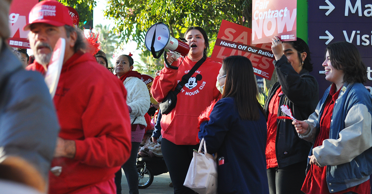 Long Beach nurses at action, with bullhorn, signs that say "Fair Contract Now" and "Save Lives: Hands off our Ratios!"