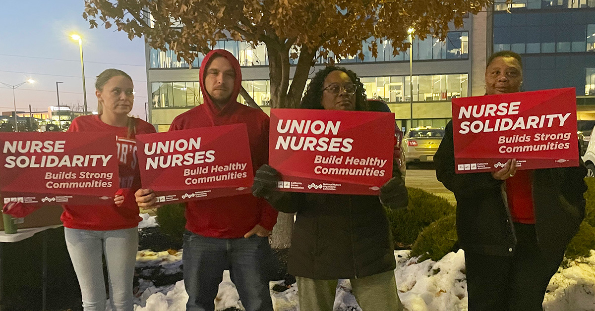 Four nurses outside Research Medical Center holding signs "Union Nurses Build Healthy Communities"