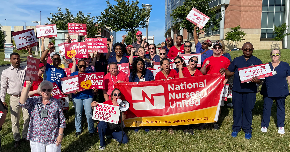 Nurses in front of St Agnes with signs: "RN Safe Staffing saves lives" and "Patients 1st in the hospital" and a "Natioanal Nurses United" banner