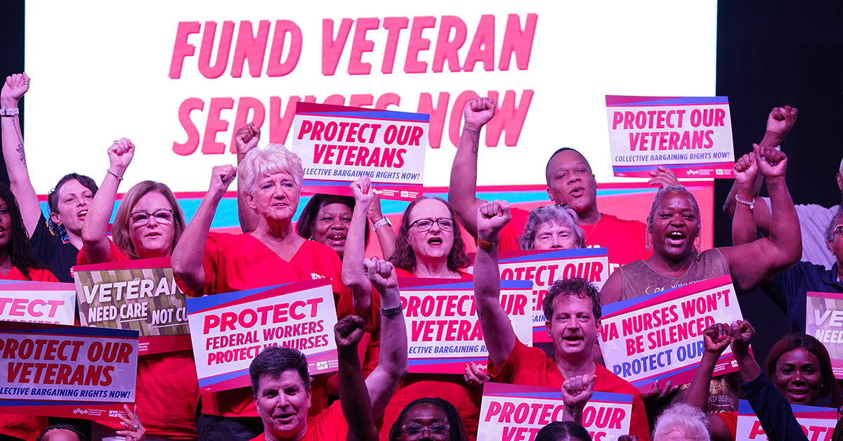 Group of nurses with raised fists holding signs supporting veterans and VA nurses