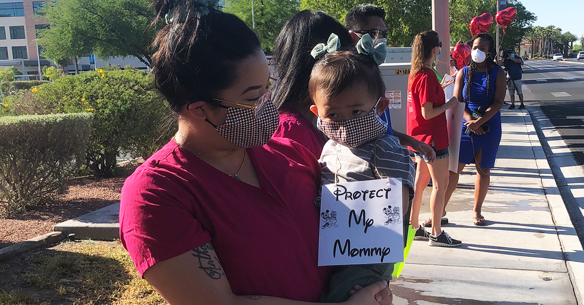 Nurse holding toddler with sign "Protect My Mommy"