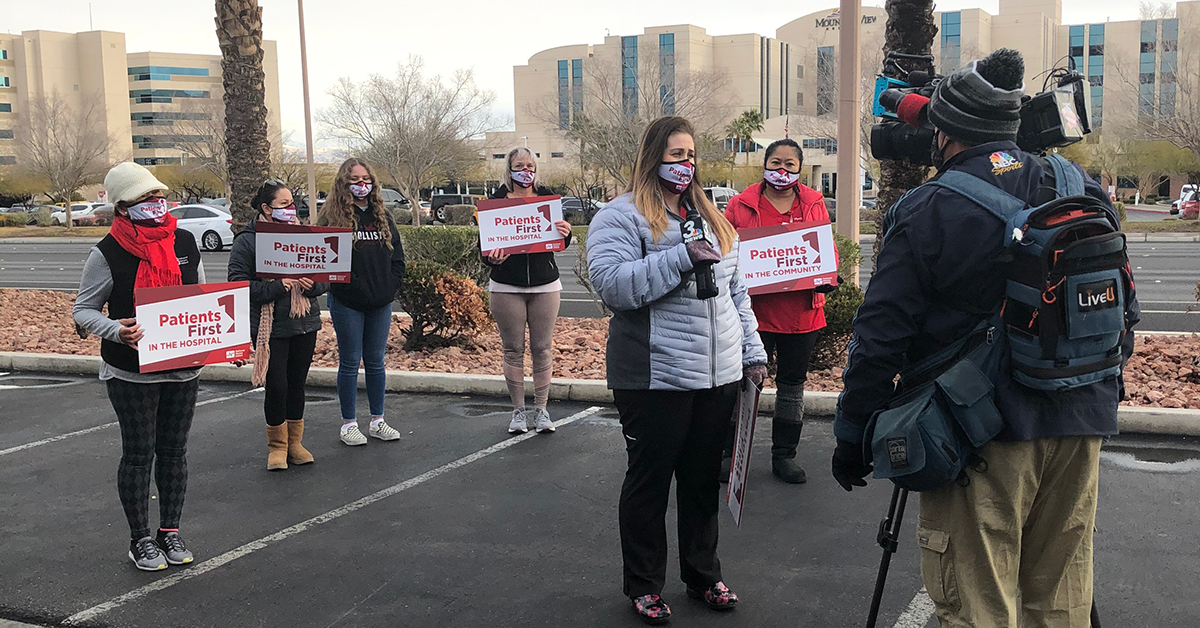 Nurses hold signs "Patients First" in front of TV camera