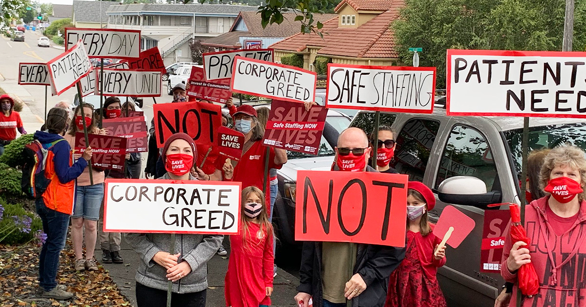 Large group of nurses and community holding signs calling for safe staffing 