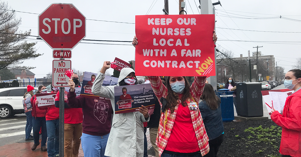Nurse outside hospital holds sign "Keep nurses local with a fair contract now!"