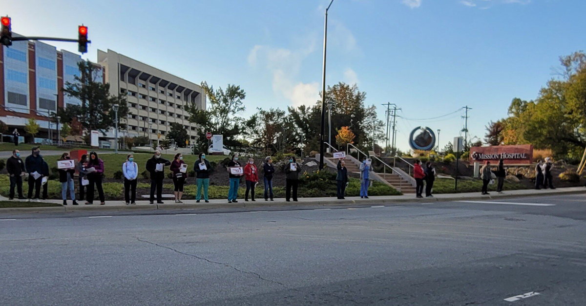 Nurses along street in front of Mission hospital holding signs