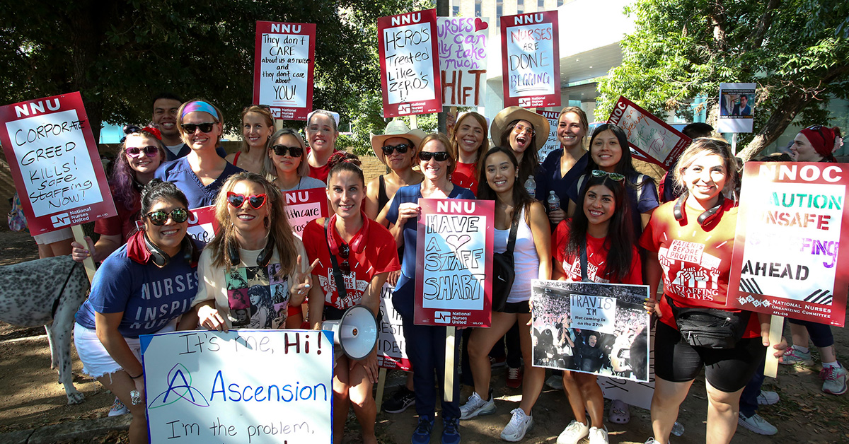 Large group of nurses hold signs demanding better treatment of nurses and patients by Ascension