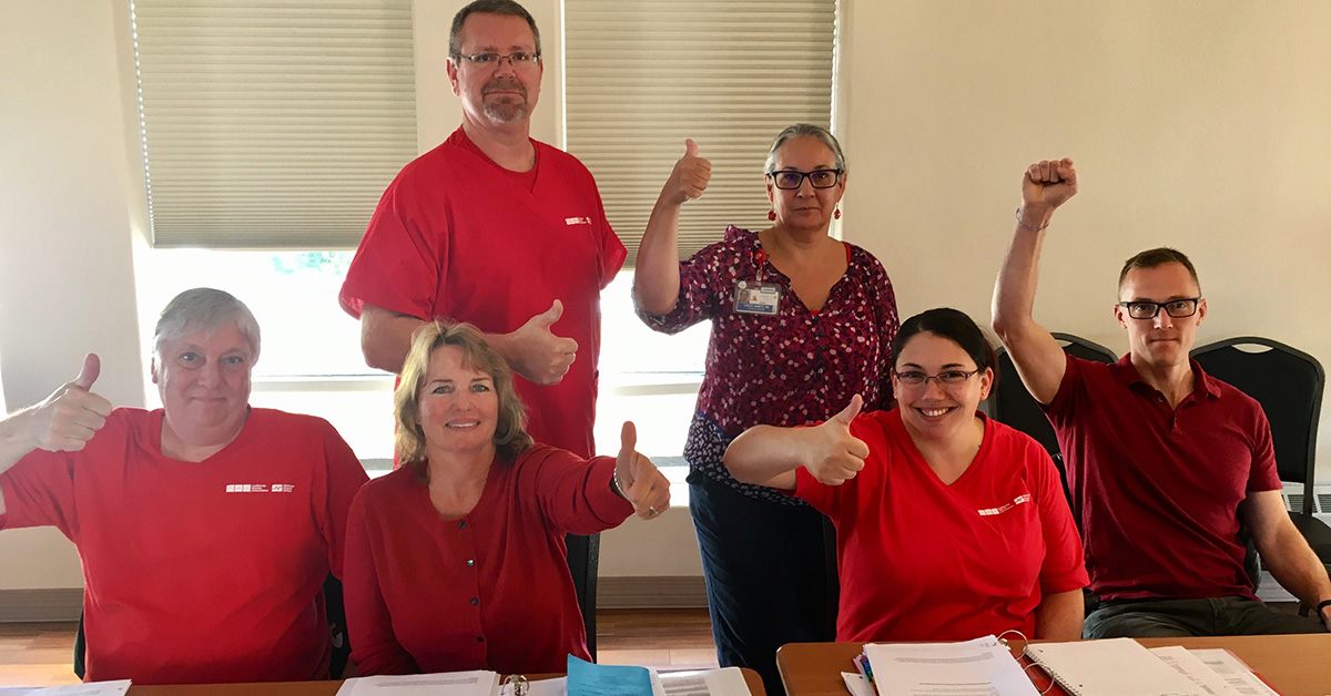 Group of nurses at table giving thumbs up