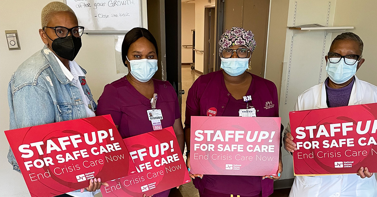 Four nurses inside hospital hold signs "Staff Up for Safe Patient Care"