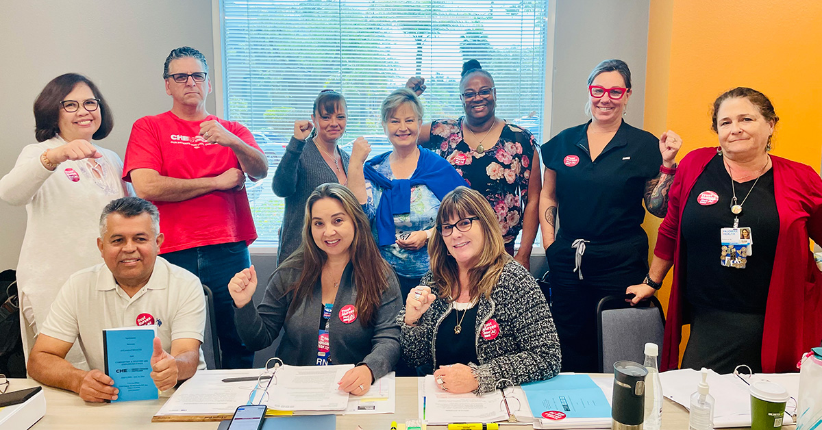 Group of nurses and health care workers inside hospital in conference room, smiling and holding raised fists