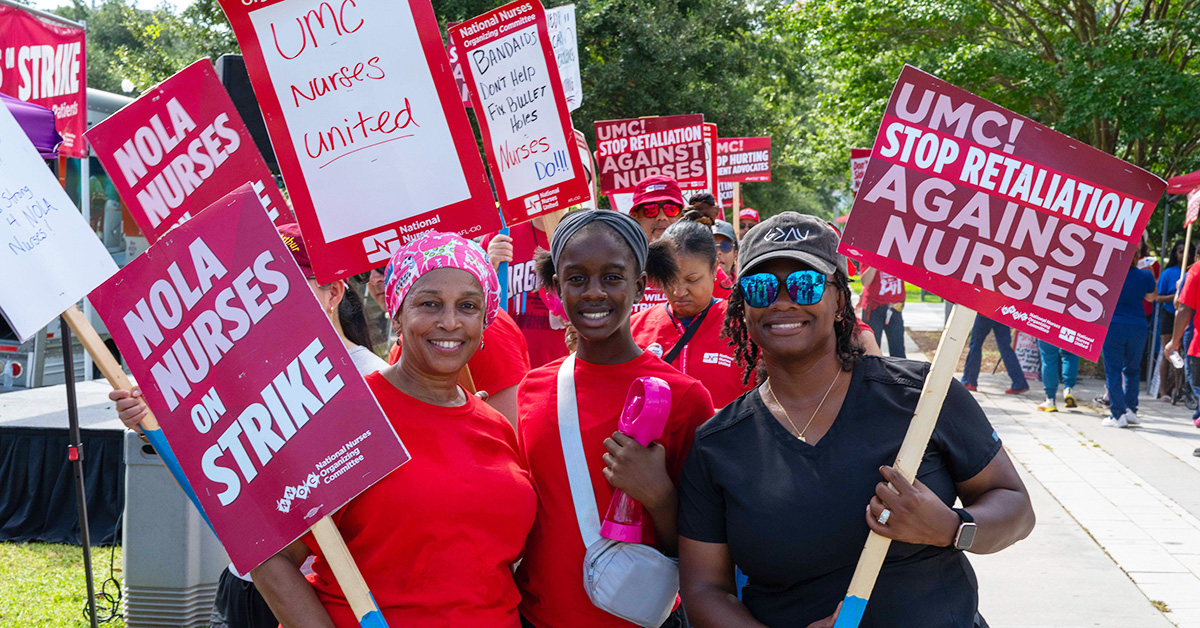 Three nurses side-by-side, smiling, holding signs calling out LCMC Health