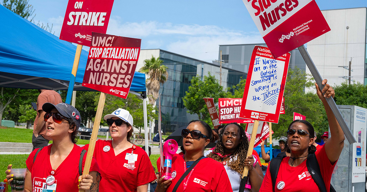 Nurses standing outside, holding signs calling for a fair contract