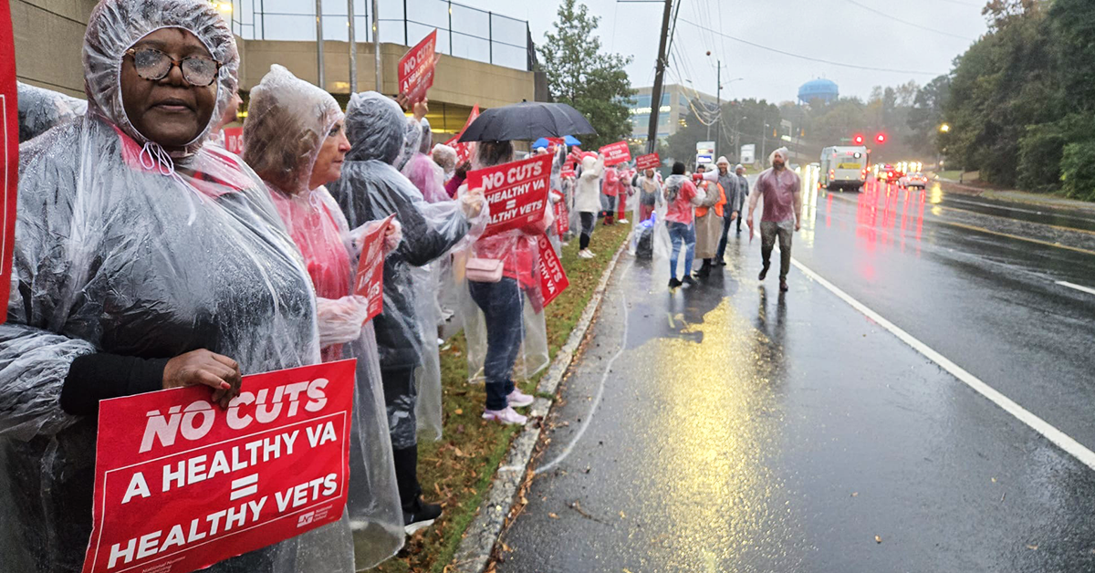 Nurses standing in rain along street with signs: "No cuts: A healthy VA = healthy vets"