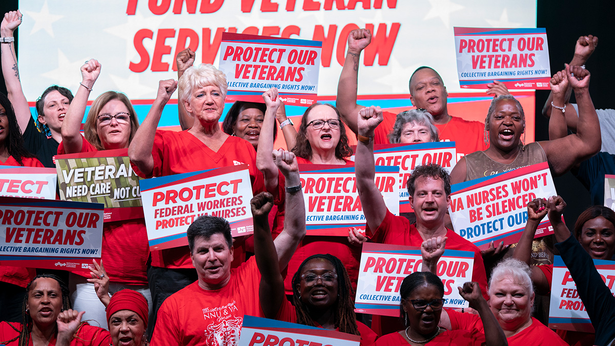 Group of nurses with raised fists holding signs supporting veterans and VA nurses