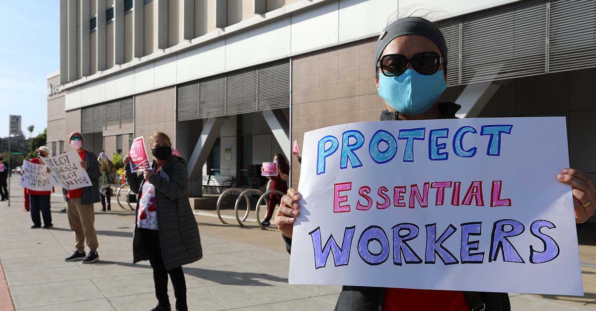 Nurse holds sign "Protect Essential Workers"