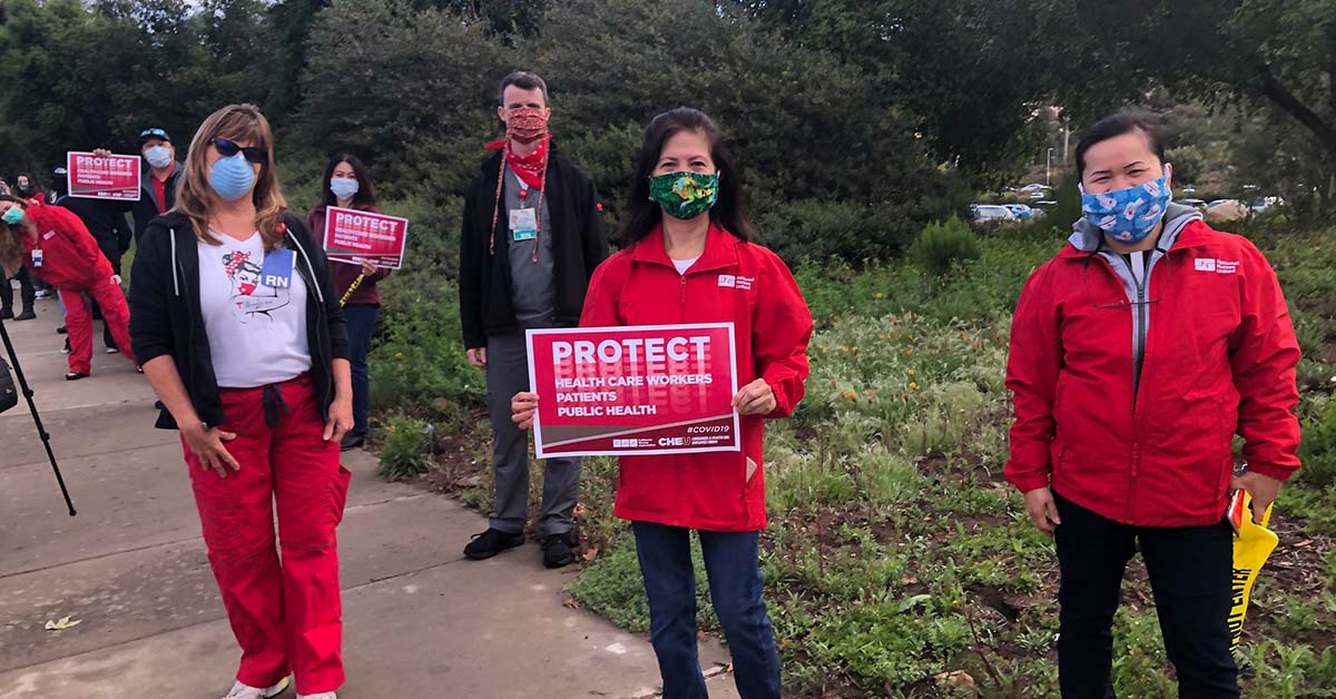 Health care workers hold signs calling for patient safety