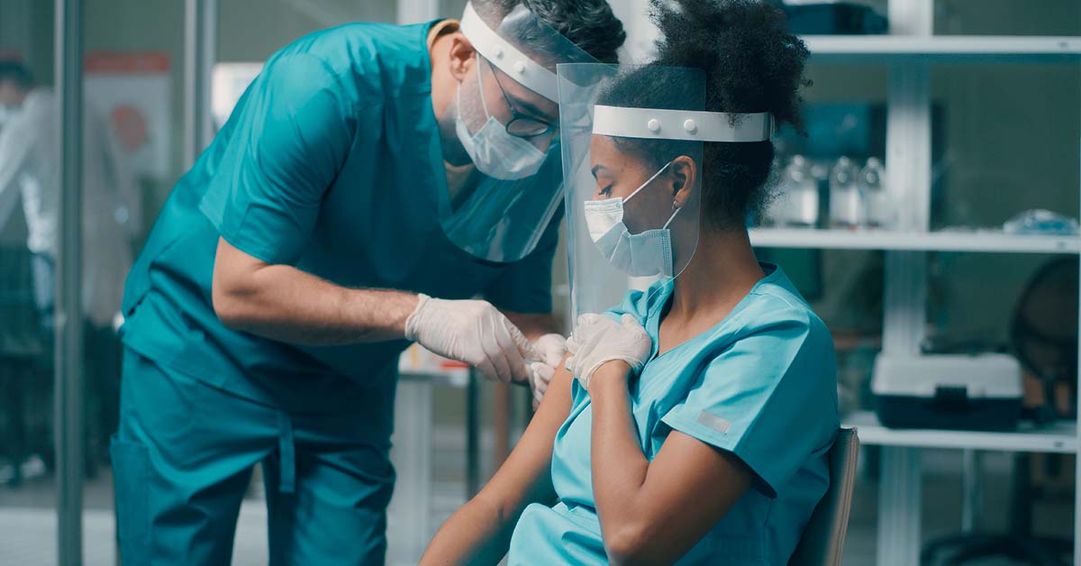 Nurse administering vaccine on another nurse