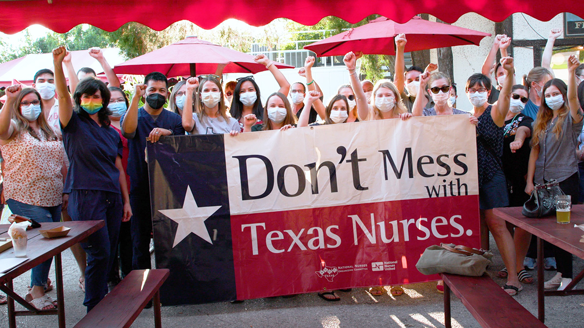 Large group of nurses outside hold sign "Don't mess with Texas nurses"