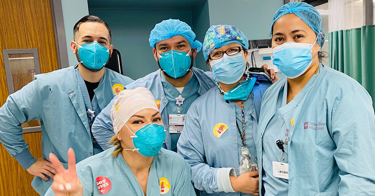 Group of five nurses inside hospital giving thumbs up