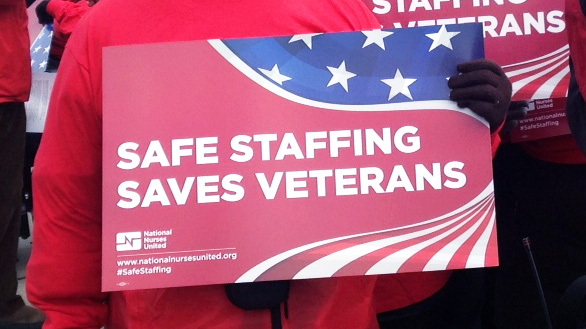 Hands hold sign "Safe Staffing Saves Veterans"