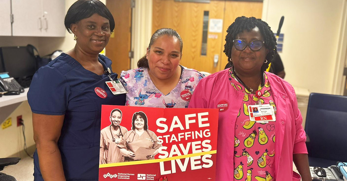 Group of three nurses inside hospital, one hold sign "Saf Staffing Saves Lives"