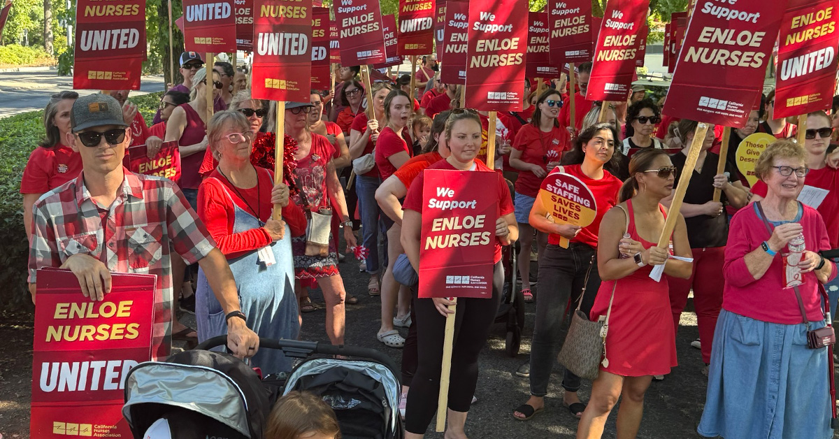 Large group of nurses outside holding signs "Enloe Nurses United"