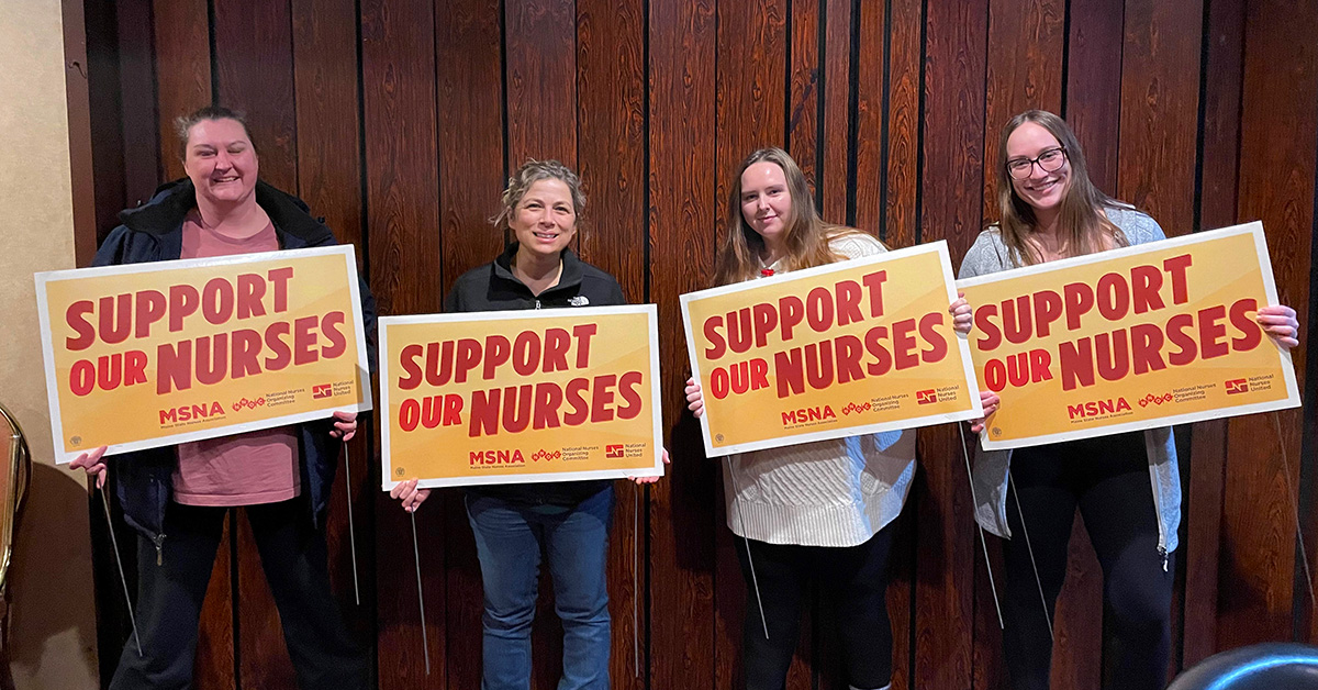 Four nurses inside holding signs "Support Our Nurses"