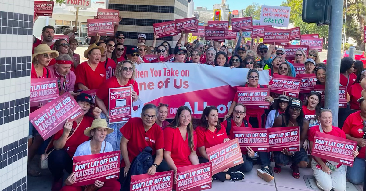 Large group of nurses holding signs "Don't lay off our Kaiser nurses"