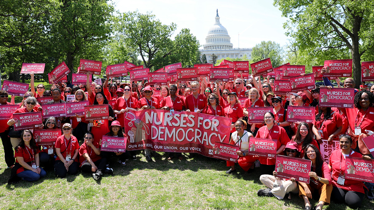 Large group of nurses holdings banner and signs "Nurses for Democracy"