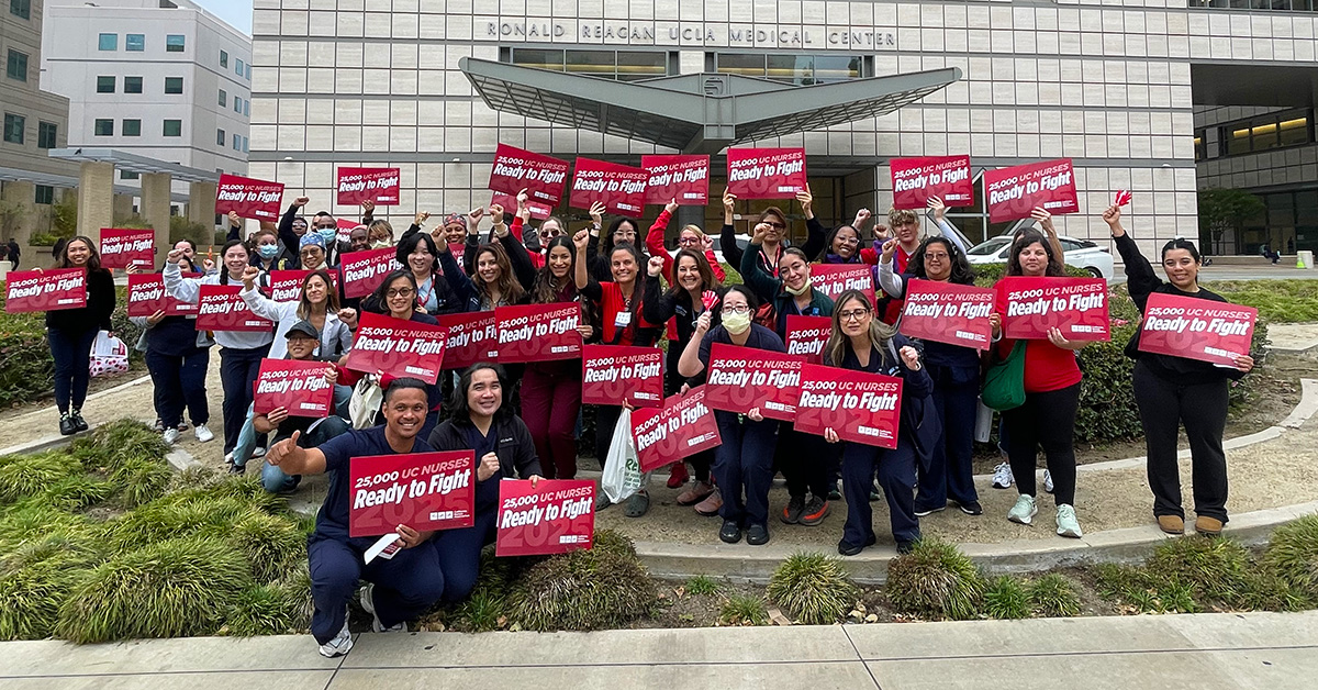 Large group of nurses outside holding signs "Ready to Fight"