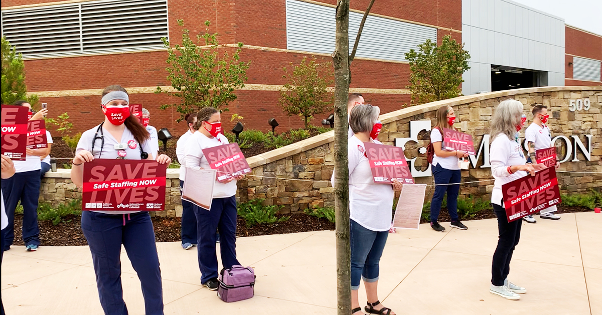 Nurses outside mission hospital hold signs "Save Lives: Safe Staffing Now"