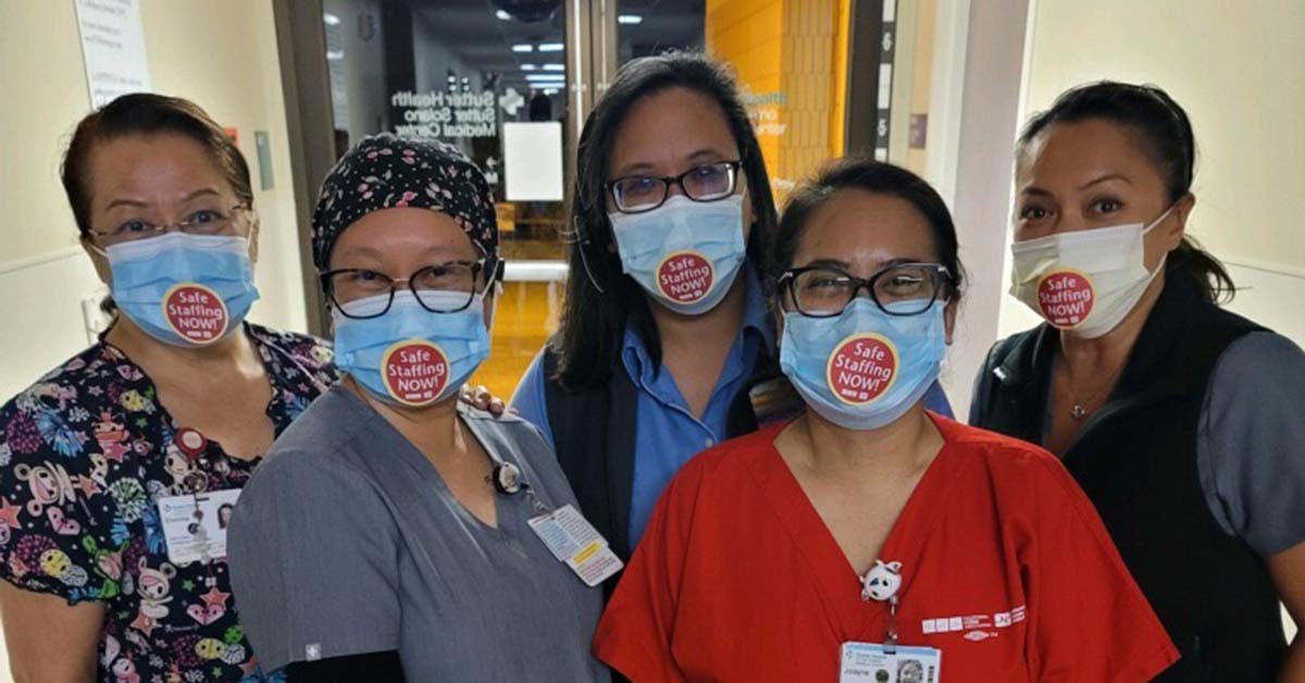 Five nurses in hospital wearing stickers that read "Safe Staffing Now"