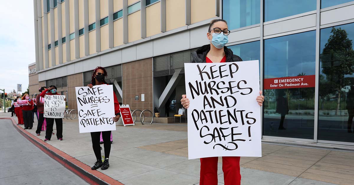 Nurses outside hospital hold signs "Keep nurses and patients safe"